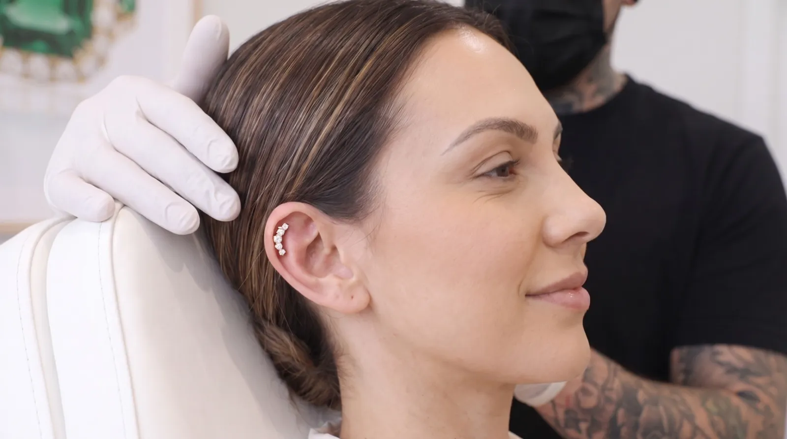 La cliente découvre son piercing en or dans le miroir du studio